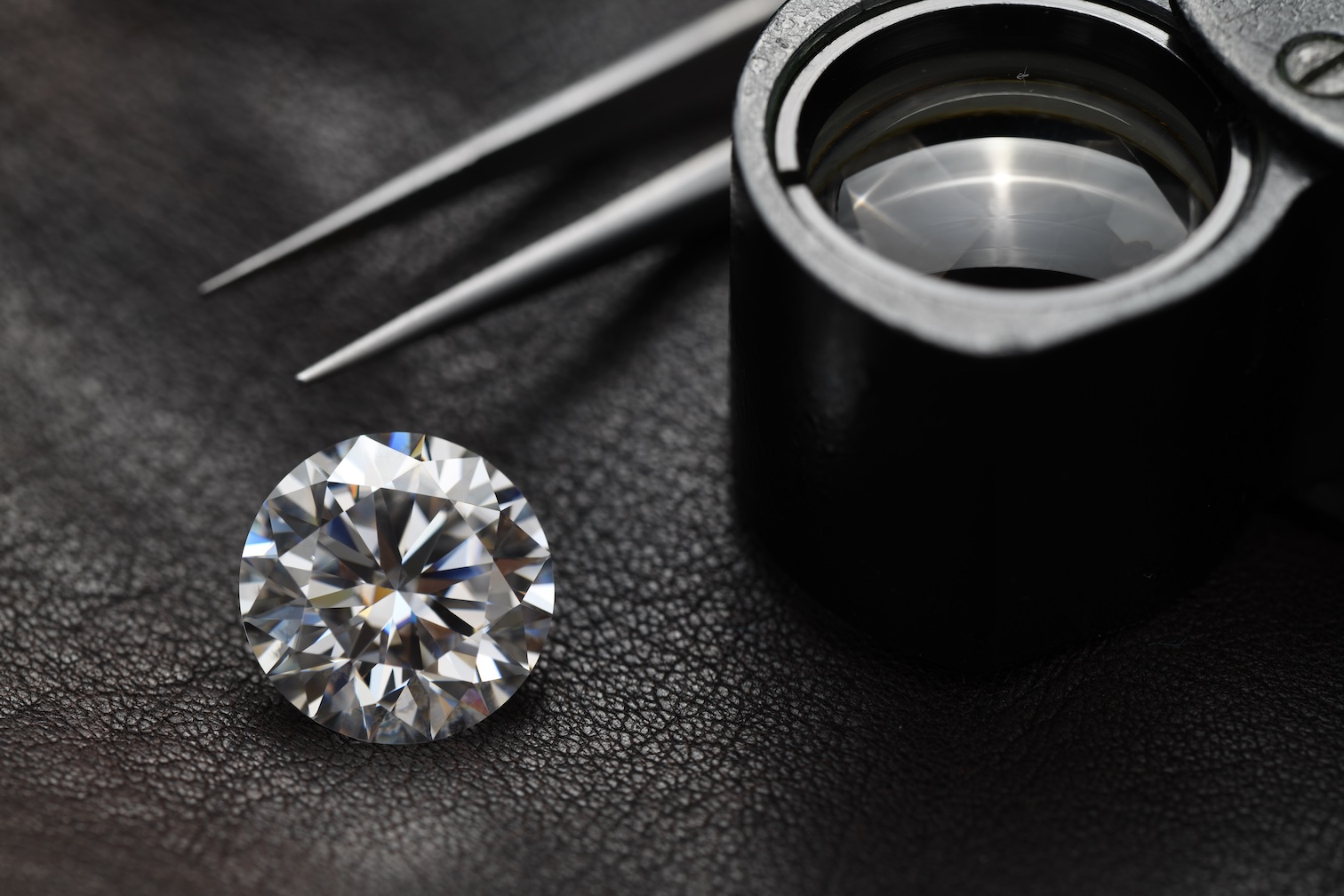 Certified diamonds: a diamond with tweezers and loupe on leather, symbolizing Judith Capital's precision, exclusivity, and access to GIA/IGI graded diamonds.